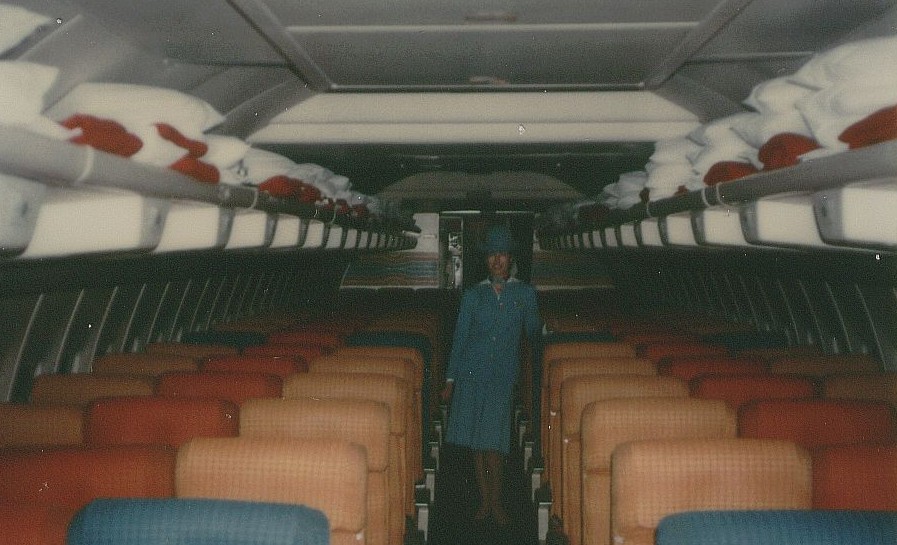 Dec 1978 A Pan Am flight attendant poses in the economy section of a 707 tail number N886PA at Washington Dulles Airport.